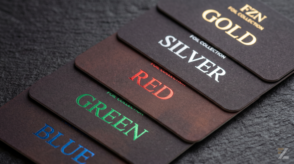 Close-up of five sample cards displaying different metallic foil colors: gold, silver, red, green, and blue.
