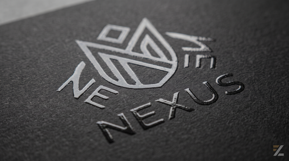 Close-up of a dark textured printed surface featuring a geometric logo and typography enhanced with glossy Spot UV detailing against a matte background.